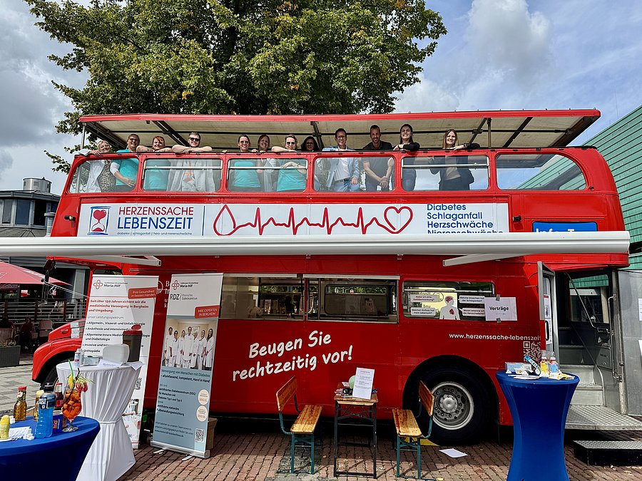 Das Team des Diabeteszentrums auf dem offenen Dach des roten Doppeldeckerbusses der Initiative Herzenssache Lebenszeit