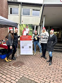 Gruppe von Frauen die draußen neben einem Roll up und einem weißen Pavillon stehen