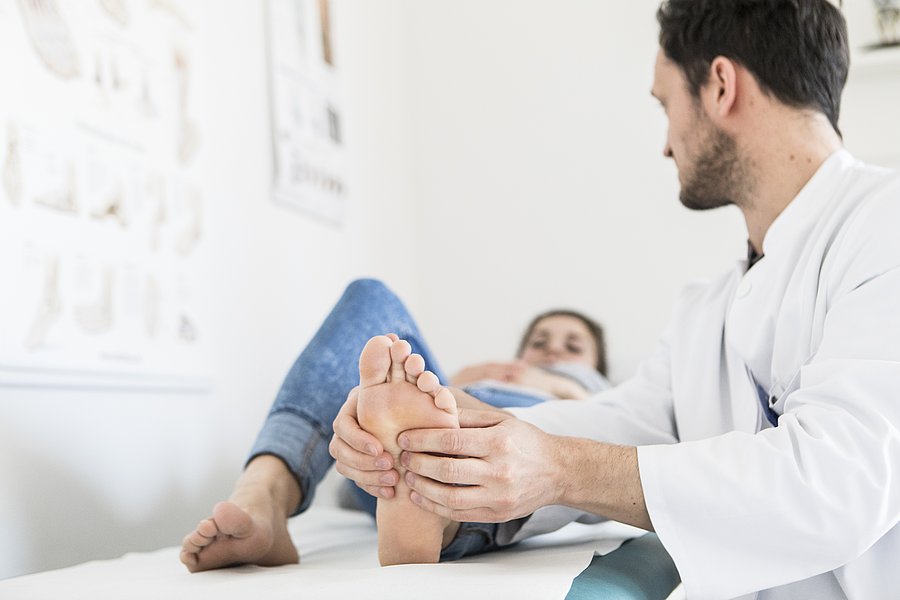 Orthopädie Matthias Kirsch untersucht den linken Fuß einer auf der Liege liegenden Patientin