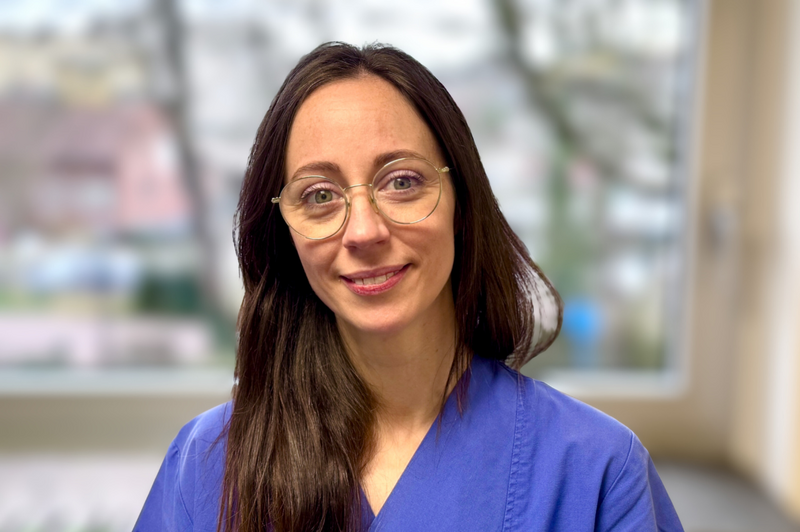 Junge Frau mit braunen Haaren und Brille und blauem Kasack