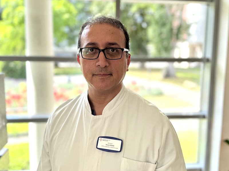 Porträt eines Arztes in weißem Kittel und mit Brille