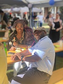 Eine Schwarzes Pärchen sitzt auf einer Bierzeltgarnitur