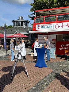 Zwei Diabetesberaterinnen in weißen Kitteln stehen jeweils an einem Stehtisch und sin im Gespräch mit Patienten