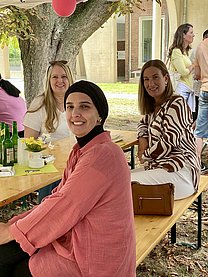 Eine Frau mit Kopftuch vorne, zwei andere Frauen hinten, alle sitzen auf einer Bierzeltgarnitur.