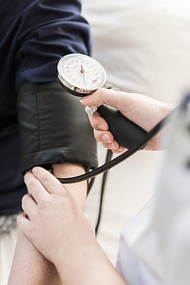 Eine Pflegerin misst bei einem Patienten Blutdruck