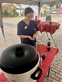 Eine junge Frau in blauer Funktionskleidung wirft Geld in eine Spendendose.