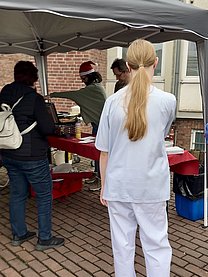Menschen stehen in einer Schlange vor einem Pavillon, in dem Waffeln gebacken werden.
