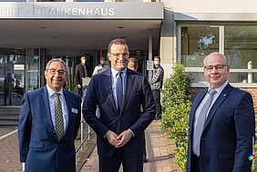 Oliver Bredel, Jens Spahn und Dr. Georg Kippels stehen vor dem Haupteingang des Maria-Hilf-Krankenhauses in Bergheim